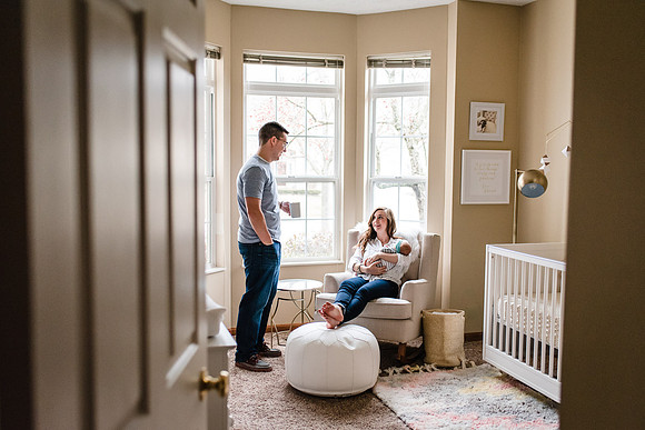 Newborn with mom on chair with dad and coffee