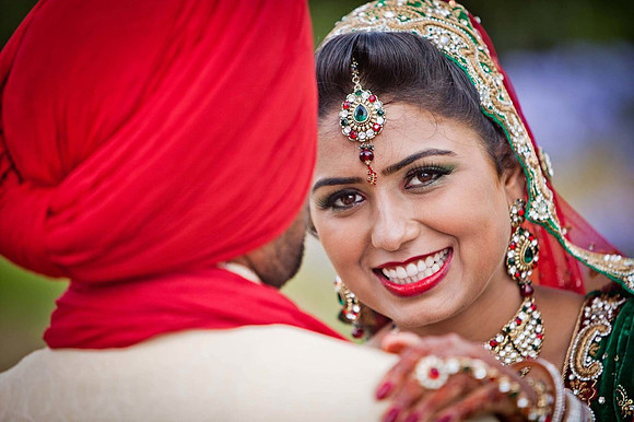 Indian Bride smiling with groom opposite direction